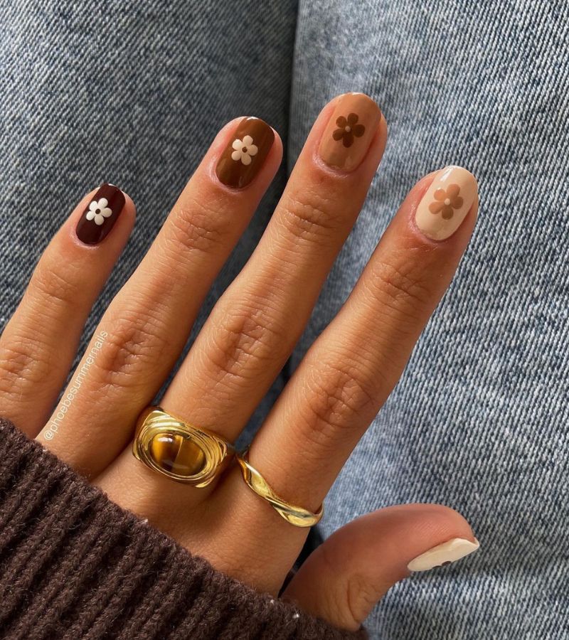 uñas marrones con flor en la parte superior 