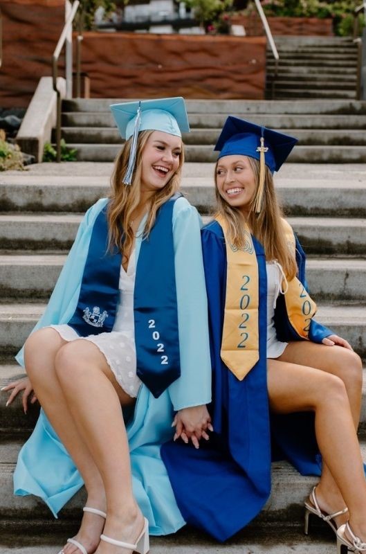 2 grad besties holding hands while sitting on stairs
