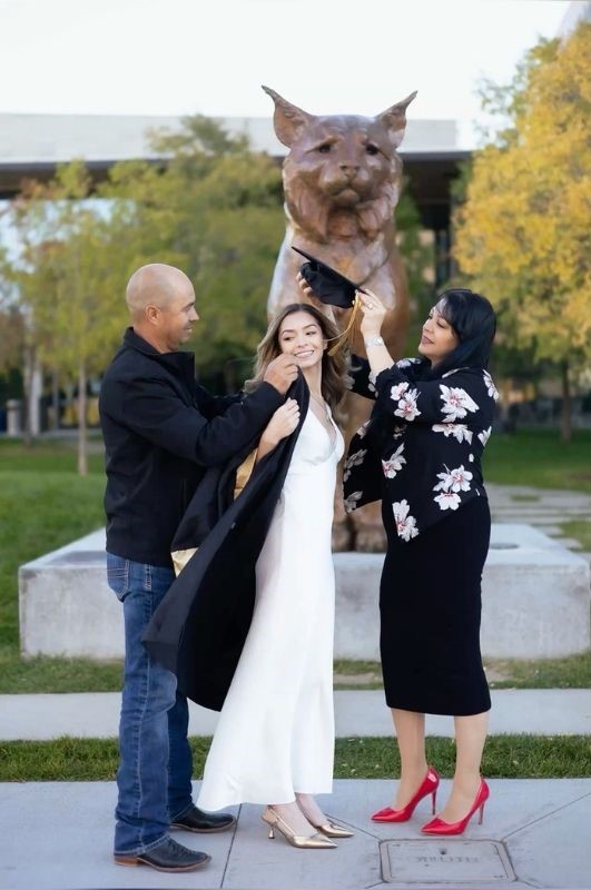 parents helping grad wear cap and gown